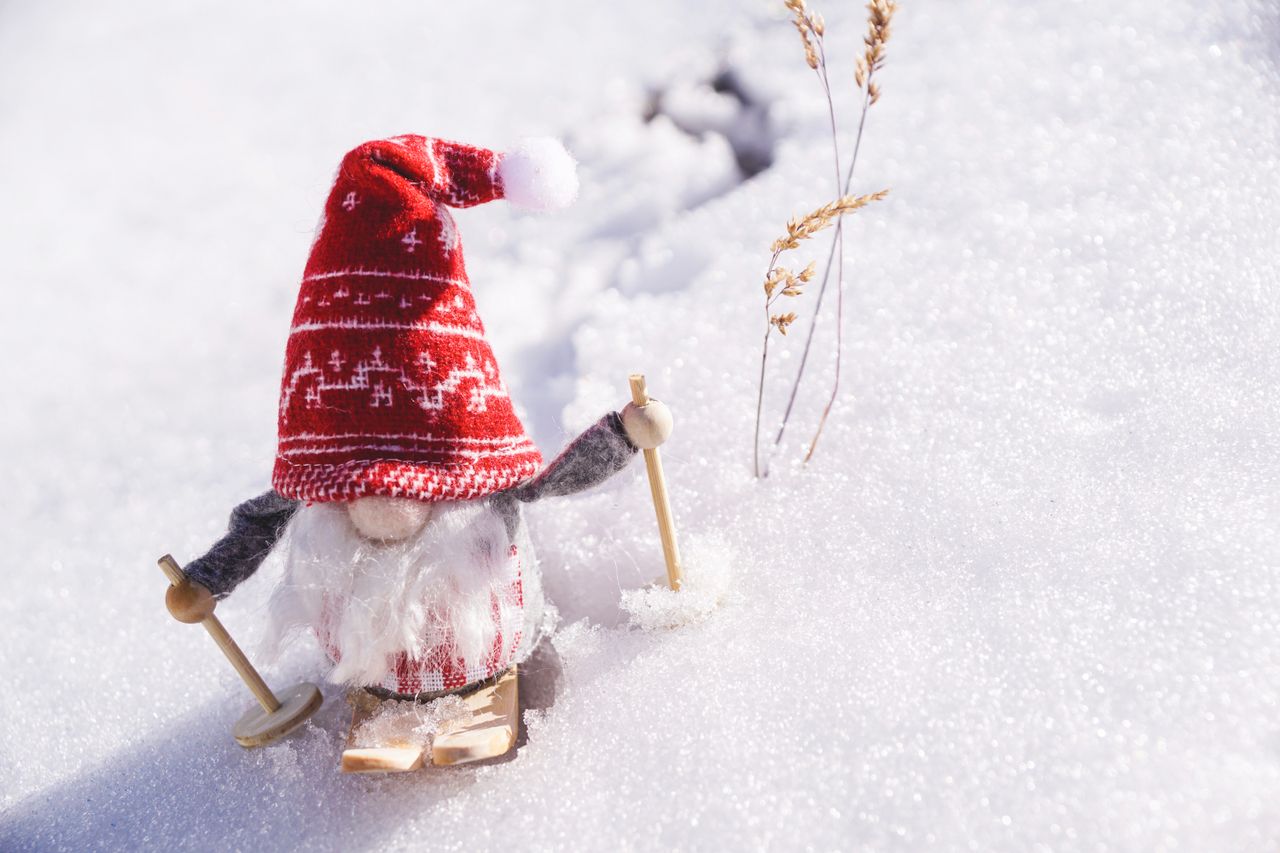 Adorable gnome figurine skiing through fresh snow, capturing the essence of winter fun.