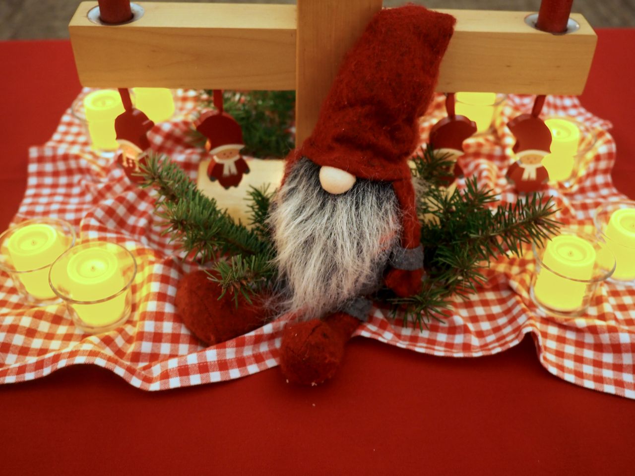 Cozy Christmas table setup with candles and a Santa gnome for holiday warmth.